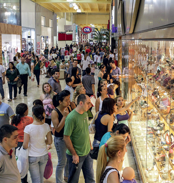 Centro de comércio movimentado; consumidores olham vitrine de loja