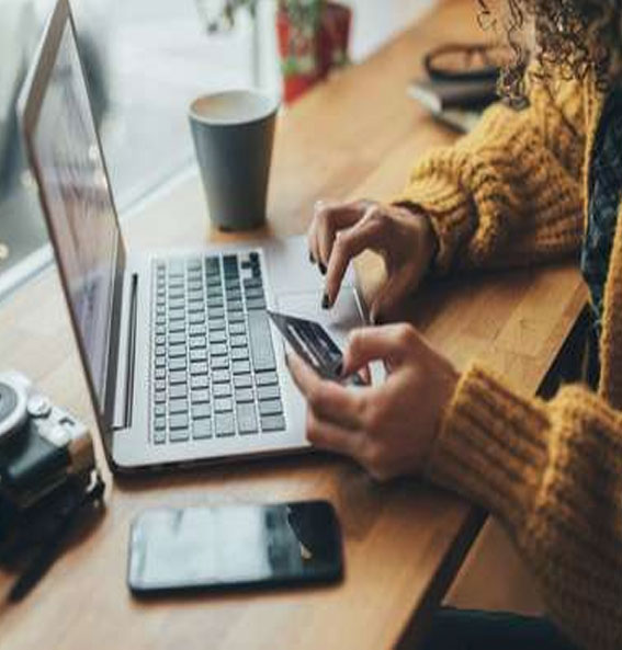 Mulher manuseia cartão e teclado de notebook para realizar compra online